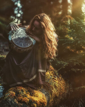 beautiful shamanic girl playing on drum in the nature. beautiful shamanic girl playing on drum in the nature